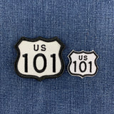 Two embroidered US Route 101 shield patches in white and black, shown on a blue denim fabric background.