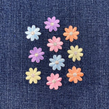 Pastel-colored flower-shaped buttons on a denim background