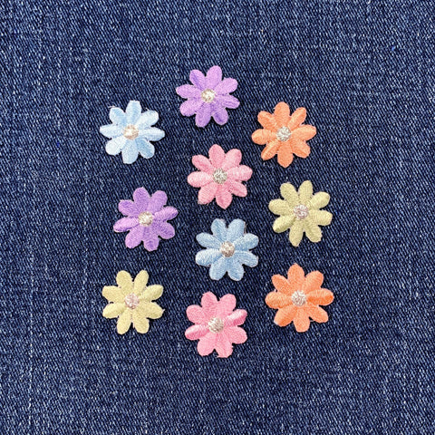 Pastel-colored flower-shaped buttons on a denim background