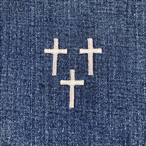 three silver cross patches on a denim background