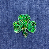 Green glittery shamrock patch on blue denim fabric
