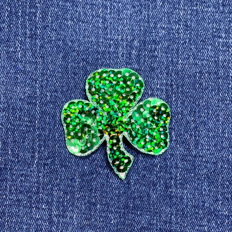 Green glittery shamrock patch on blue denim fabric