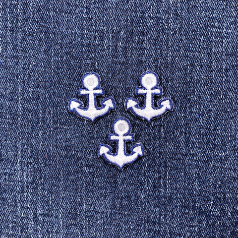 Three embroidered patches depicting anchors in blue and white colors on a denim background.