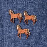 Three embroidered horse patches on a denim background