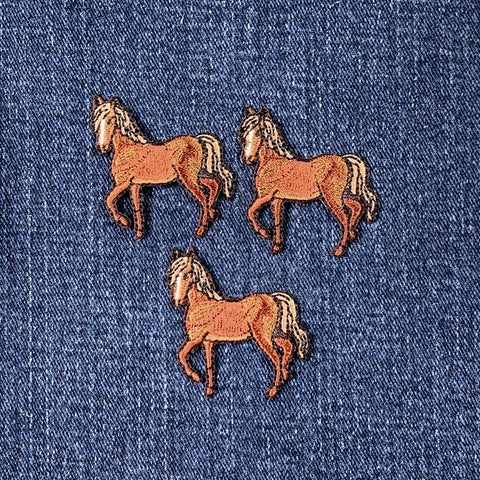 Three embroidered horse patches on a denim background
