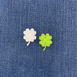a green and a white 4 leaf clover patch on a denim background