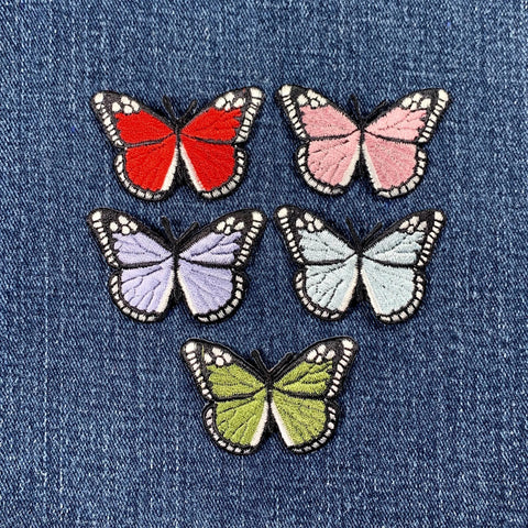 Five colorful butterfly patches on a denim background