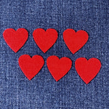 Six red heart-shaped patches on blue denim fabric