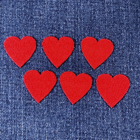 Six red heart-shaped patches on blue denim fabric