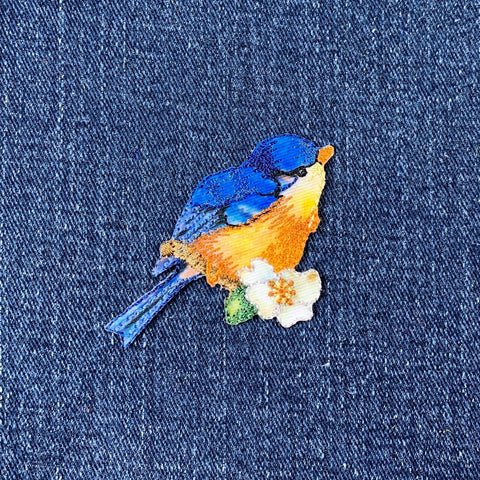 Embroidered bluebird patch on denim fabric