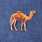 Embroidered camel applique patch with a brown and beige design on a denim background.