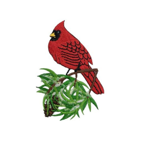 An embroidered patch of a red cardinal perched on a green pine branch with white snow, isolated on a white background.