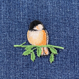 Embroidered bird patch on denim fabric