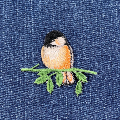 Embroidered bird patch on denim fabric