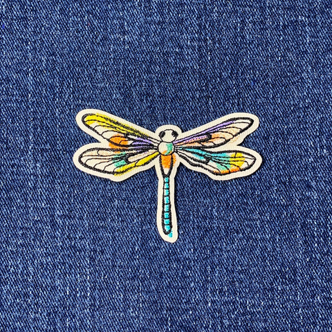 Colorful dragonfly patch on blue denim fabric