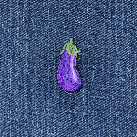 Embroidered purple eggplant patch on a denim background