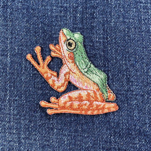 Embroidered frog patch on denim fabric