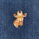 Embroidered giraffe patch on a denim fabric background