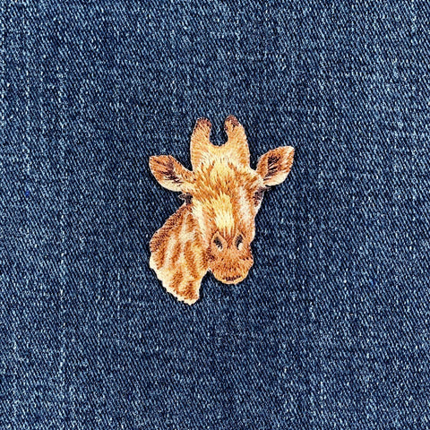 Embroidered giraffe patch on a denim fabric background