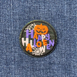 Halloween-themed patch with a pumpkin and spider webs on denim fabric.