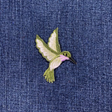 Embroidered hummingbird patch on denim fabric