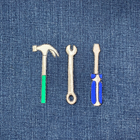 Three tool patches (hammer, wrench, screwdriver) on a denim background