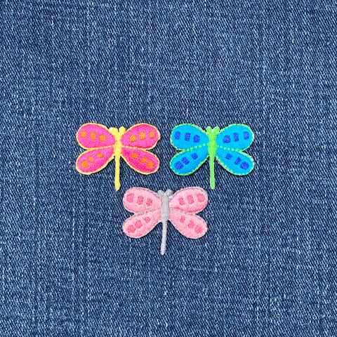 Three colorful dragonfly patches on denim fabric