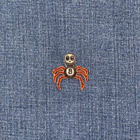 Spider with a skull head patch on blue denim fabric