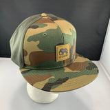 Camouflage baseball cap with a LET'S BE IRIE logo patch on a mannequin head against a black background