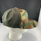 Camouflage baseball cap with a LET'S BE IRIE logo patch on a mannequin head against a black background
