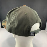 Green cap on a mannequin head with a visible brand logo against a dark background