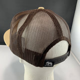 Beige cap with brown mesh and 'Let's Be Irie' fabric tag on a black background