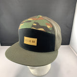 Camouflage trucker hat with a black front panel, an olive bill, and 'Let's Be Irie' patch on a black background