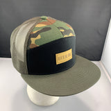 Camouflage trucker hat with a black front panel, an olive bill, and 'Let's Be Irie' patch on a black background
