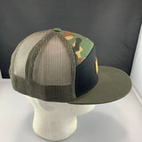 Camouflage trucker hat with a black front panel, an olive bill, and 'Let's Be Irie' patch on a black background