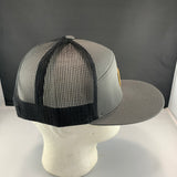 Gray trucker hat with black mesh back on a mannequin head against a gray background