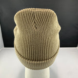 Beige knit beanie on a mannequin head against a black background