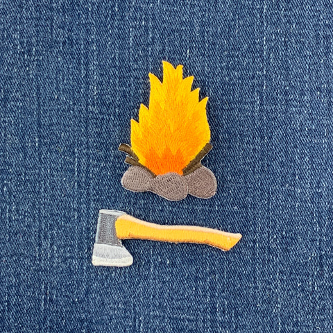 Embroidered patch of a campfire and axe on denim fabric