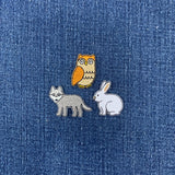 Three animal patches (owl, wolf, rabbit) on a denim background