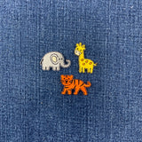 Three animal patches (elephant, giraffe, and tiger) on a blue denim background