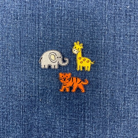 Three animal patches (elephant, giraffe, and tiger) on a blue denim background