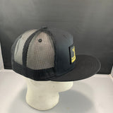 Black and gray mesh cap on a mannequin head with a logo against a dark background
