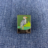 A rectangular enamel pin featuring a heron in a marsh with the text 'EVERGLADES NATIONAL PARK' at the bottom, placed on blue denim fabric.
