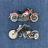 Two embroidered motorcycle patches on a blue denim fabric background. 