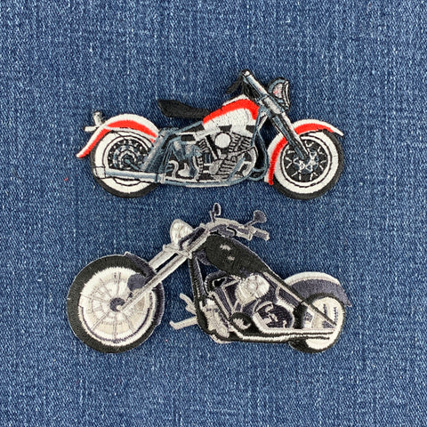 Two embroidered motorcycle patches on a blue denim fabric background. 