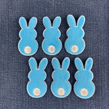 six fuzzy blue bunny patches on a denim background