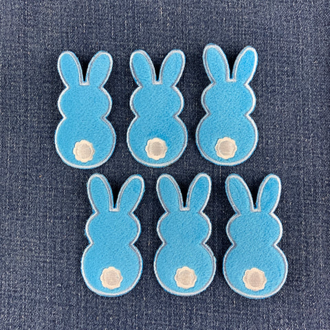 six fuzzy blue bunny patches on a denim background
