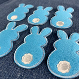 six fuzzy blue bunny patches on a denim background