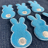 six fuzzy blue bunny patches on a denim background