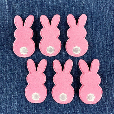 six fuzzy pink bunny patches on a denim background